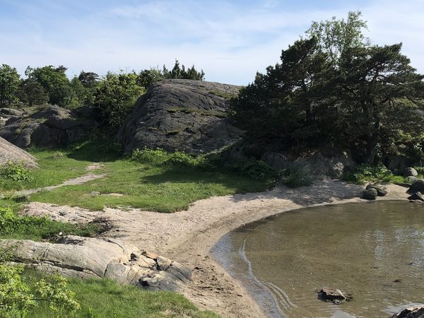 Liten vik med sand og svaberg